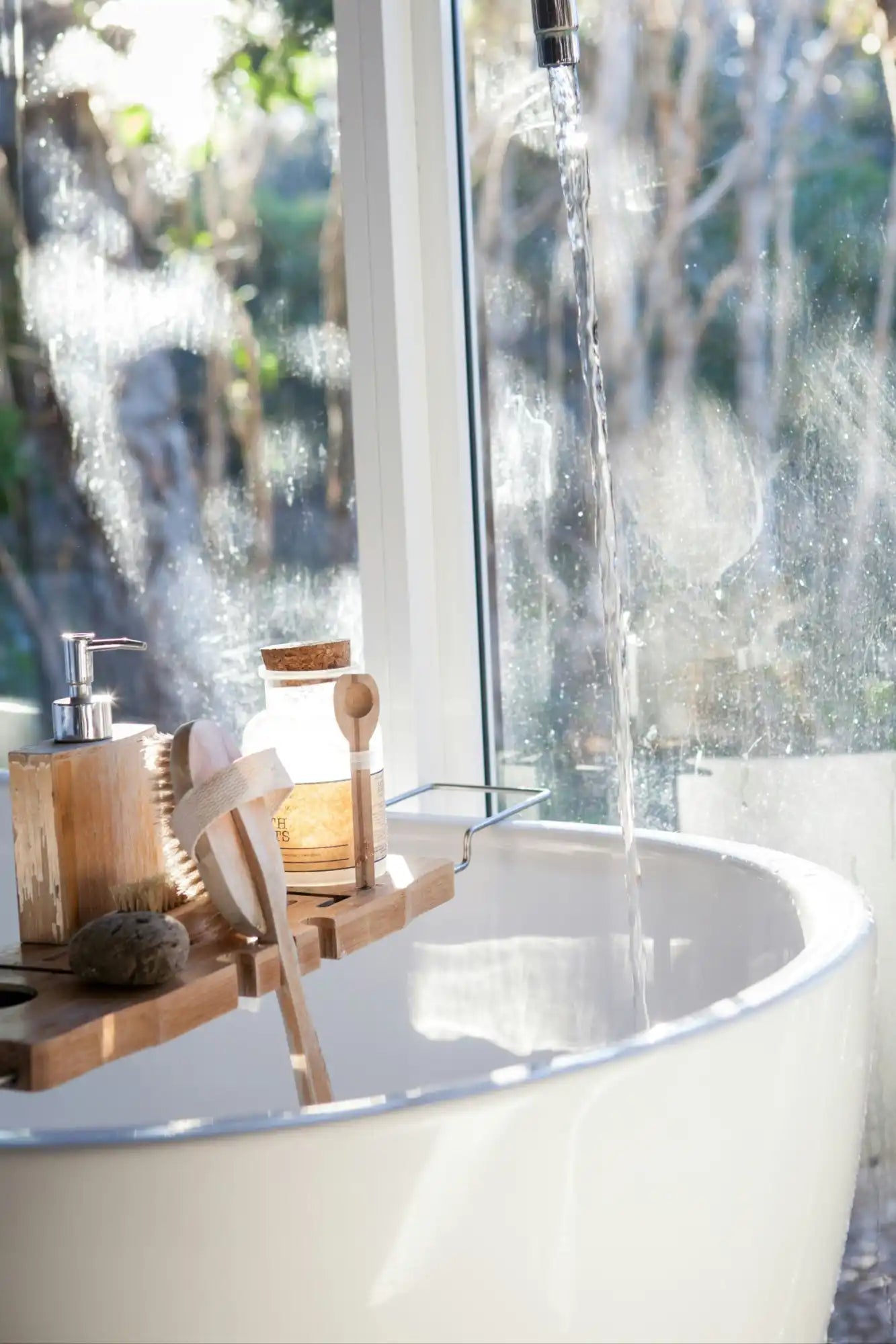Bathtub with wooden tray and bath products.